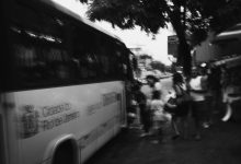 Passageiros embarcam em um ônibus urbano; a imagem em preto e branco registra o movimento de usuários do transporte coletivo.
