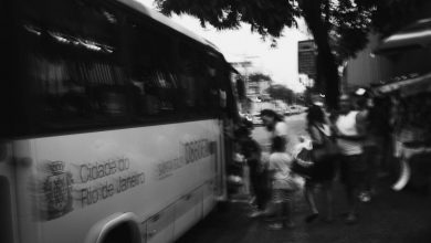 Passageiros embarcam em um ônibus urbano; a imagem em preto e branco registra o movimento de usuários do transporte coletivo.