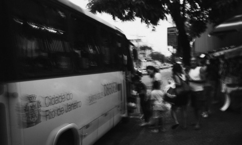 Passageiros embarcam em um ônibus urbano; a imagem em preto e branco registra o movimento de usuários do transporte coletivo.
